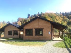 a small wooden cabin with a fence and trees at Bieszczadzki Luz in Dwernik