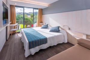 una habitación de hotel con una cama y un balcón en GHT Sa Riera, en Tossa de Mar 37 fotos más