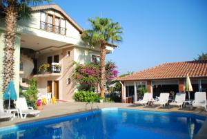 a swimming pool in front of a house with palm trees at Crescent Hasirci Hotel in Dalyan
