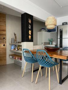 eine Küche mit einem Holztisch und blauen Stühlen in der Unterkunft 13-A - Apto 2 dorms c/ar condicionado + 1vaga in Guarujá
