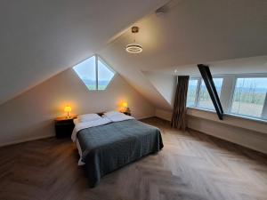 a attic bedroom with a bed and two lamps at Erve Lindehof in Lochem
