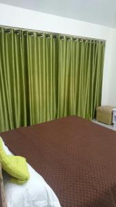 a bedroom with a bed with a green curtain at Ooty Blue Mountain Villa Thalayathimund in Ooty +2 photos