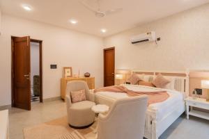 a bedroom with a large bed and two chairs at ELIVAAS Villa Paraiso 4 BHK with Pool & Bar in Camorlim