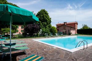 a swimming pool with lounge chairs and an umbrella at Agriturismo Santa Barbara in Mira