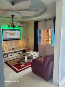 Una sala de estar con un sofá y un televisor. en Résidence LYONNAISE ODZA, en Yaoundé