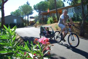 un hombre montando una bicicleta con un cochecito de bebé en Lagrange Grand Bleu Vacances – Résidence Les Pescalunes, en Agde