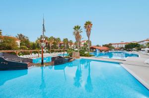 una piscina in un resort con sedie e palme di PortAventura Hotel El Paso - Includes unlimited access to PortAventura Park & 1 access to Ferrari Land a Salou
