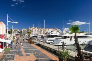 a marina with boats and people walking on a sidewalk at Lagrange Grand Bleu Vacances – Résidence Les Pescalunes in Agde