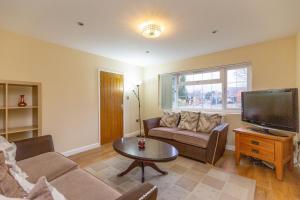 ein Wohnzimmer mit Sofa und Fernseher in der Unterkunft Wootton 2-Bedroom Bungalow in Hardingstone