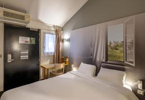 une chambre avec un grand lit blanc et une fenêtre dans l'établissement B&B HOTEL Bordeaux Lormont, à Lormont