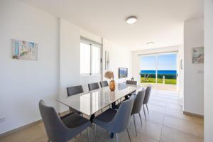 a dining room with a table and chairs and the ocean at Villa Bella Ena in Nea Dimmata