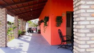 eine orangefarbene Wand mit einem Stuhl auf einer Terrasse in der Unterkunft Casa de Praia Toca da Onça in São Miguel do Gostoso