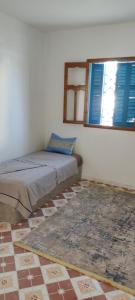 a bedroom with a bed and a window and a rug at appartement à louer Djerba in Al Maqārisah