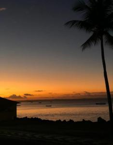 una puesta de sol en la playa con una palmera en ILHA De ITAPARICA PONTA DE AREIA CASA DA NÉIA TEMPORADA, en Itaparica 22 fotos más