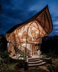 a bamboo house with a curved roof at night at Wiwaka Harmony in Nature in Selat