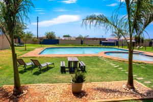 a picnic table and two palm trees next to a swimming pool at Lempitse Lodge in Polokwane