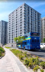 a blue bus driving down a street in front of a tall building at Clove Beach Hulhumale in Male City