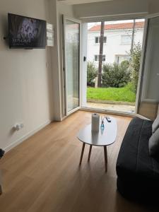 a living room with a couch and a table at Appartement 1 chambre vu sur jardin Appart A in La Roche-sur-Yon