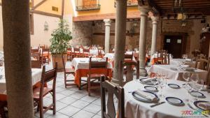 a restaurant with tables and chairs with white tablecloths at Hotel Las Cancelas in Ávila