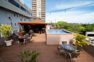 a balcony with tables and chairs and a pool on a building at Tarobá Hotel in Foz do Iguaçu