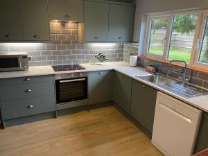 eine Küche mit grünen Schränken und einem Waschbecken in der Unterkunft Landews Meadow Cottages in Badlesmere