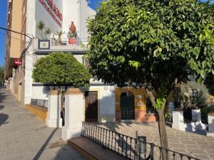 a tree in front of a building with a fence at Casa Puente ROMANO cerca de Sevilla in Alcalá de Guadaira +4 photos
