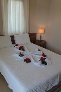 a white bed with red flowers on it at Crescent Hasirci Hotel in Dalyan