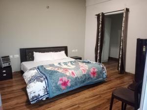 ナイニタールにあるNainigreen Valley Kainchidham Luxurious Homestayのベッドルーム1室(花の咲く毛布と鏡付きのベッド1台付)