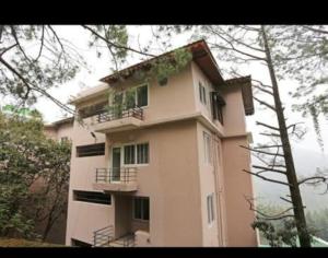 ナイニタールにあるNainigreen Valley Kainchidham Luxurious Homestayの側面にバルコニーがある高層ビル