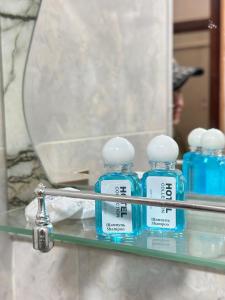 three blue bottles on a shelf in front of a mirror at Khiva Rajab Ota in Khiva
