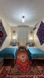 two beds in a room with a rug at Khiva Rajab Ota in Khiva