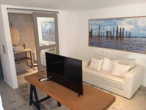 a living room with a white couch and a flat screen tv at Inn Tribus Hotel in Flecheiras