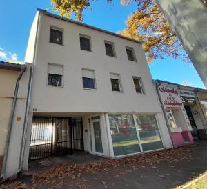 a white building with a store in front of it at Freedom 50 Apartman in Pécs
