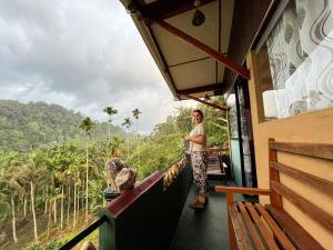 a man is standing on the balcony of a house at Rainforest View in Deniyaya