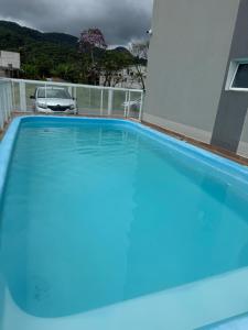a swimming pool with blue water in front of a house at Apartamento novo em Matinhos 2 piscinas in Matinhos