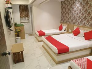 ein Hotelzimmer mit zwei Betten und einem Fernseher in der Unterkunft Hotel Gulf in Mumbai