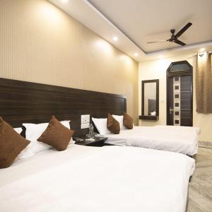 two beds in a hotel room with white sheets at Hotel Siddharth A Boutique Guest House in New Delhi