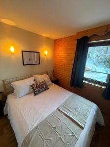 a bedroom with a large white bed with a window at "La Croix", Appartement 4 personnes, les Balcons de Recoin in Chamrousse