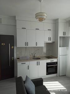 a kitchen with white cabinets and a black refrigerator at ŞAHİNER APART Otel in Finike