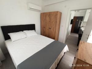 Schlafzimmer mit einem weißen Bett und einem Holzschrank in der Unterkunft ŞAHİNER APART Otel in Finike + 37 Fotos