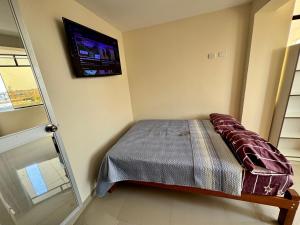 a bedroom with a bed and a tv on the wall at Habitaciones Chincha in Sunampe