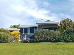 una casa azul con césped delante en Redtail Ridge Cottages, en Hester