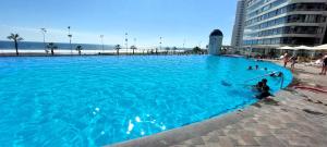 a large blue swimming pool next to a beach at Departamentos Mar Egeo in Iquique