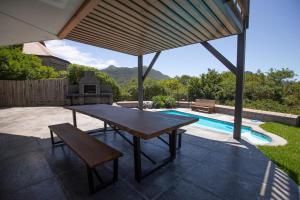 un patio con mesa, banco y piscina en Bright and spacious home with private pool, en Ciudad del Cabo