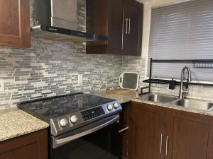 a kitchen with a stove top oven next to a sink at 3 bedroom central location montreal close to airport in Laval +14 photos