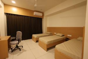 a hotel room with two beds and a desk at Hotel Devbhoomi Prime in Khambhāliya +8 photos