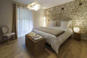 a bedroom with a large bed with a stone wall at Gîte 1694 - 4 étoiles - proche Futuroscope in Scorbé-Clairvaux +59 photos
