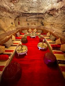 a room in a cave with tables and red carpet at Kasbah El Hajja in Aït Benhaddou +35 photos
