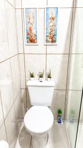 a bathroom with a toilet with two pictures on the wall at Casa das borboletas in Matinhos +16 photos