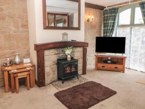 un soggiorno con camino e televisione di Old Hall Cottages ad Ashbourne